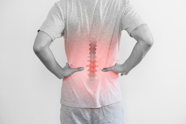 Man with his hands to his hips indicating back pain overlaid with graphic image of spine