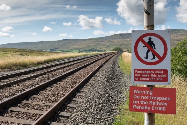 Railway no trespass sign in the landscape with railway track in foreground