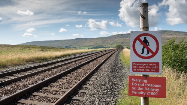 Railway no trespass sign in the landscape with railway track in foreground