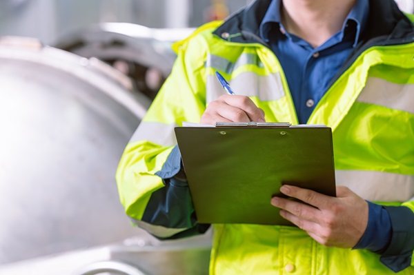 Man wearing PPE with a clipboard for fault reporting