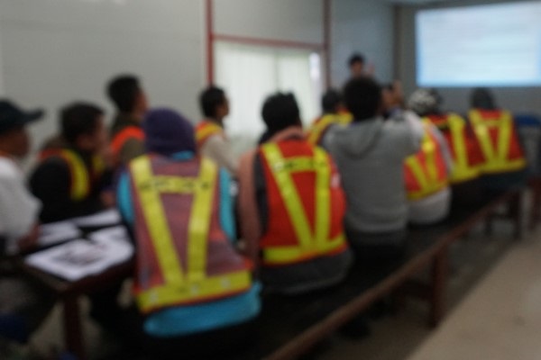 Blurred photo of someone giving a presentation to frontline workers on site