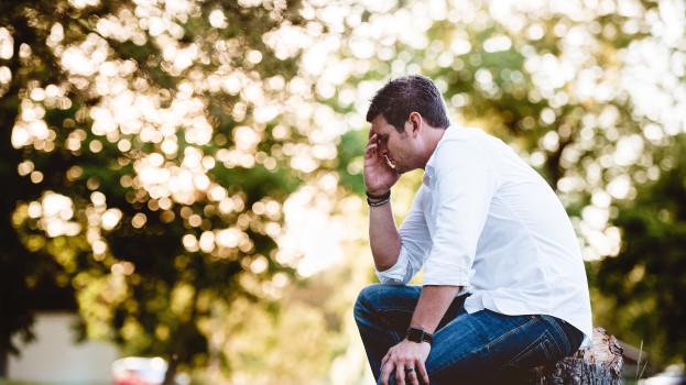 Man sitting outside with his head in his hand