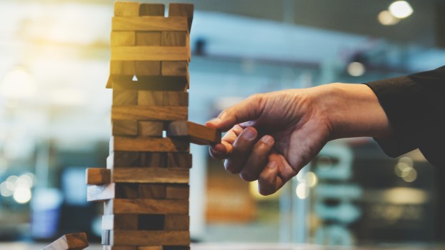 Hand pulling out a jenga game block to represent change risk