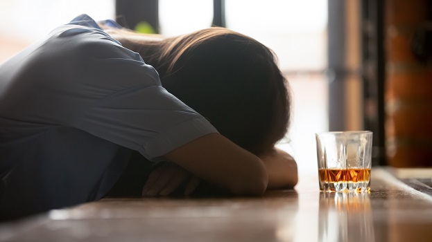 Drunk woman hunched over with a glass of alcohol
