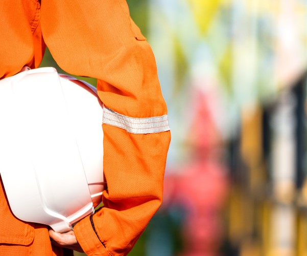 Someone in PPE with white hard hat tucked under arm