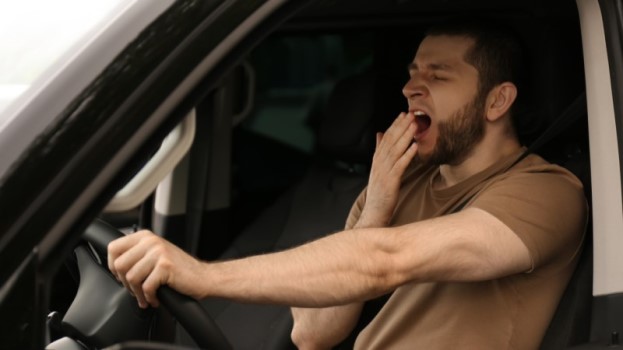 Man driving while yawning
