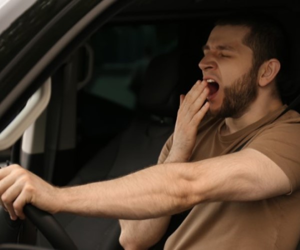 Man driving while yawning