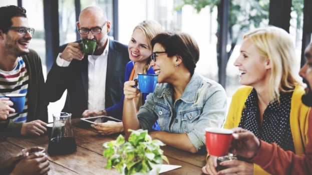 People chatting around a table drinking coffee