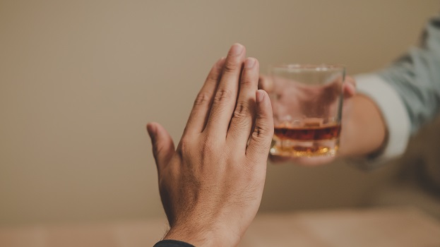 A hand pushes away an alcoholic drink being offered