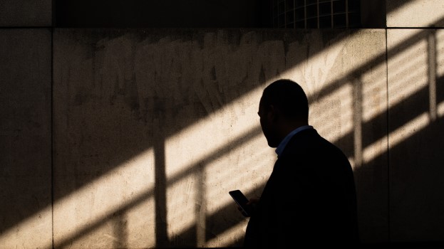 Man in shadows looking at phone