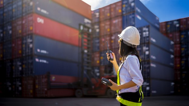 Woman using walkie-talkie managing cargo port operations 