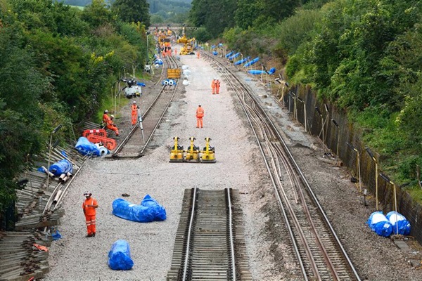Trackworkers working with machines, and materials on a railway track.