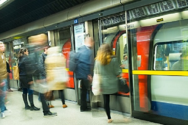 London Underground train pulls into a station, passengers waiting on platform to alight.