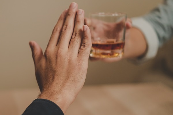 A hand pushes away an alcoholic drink being offered