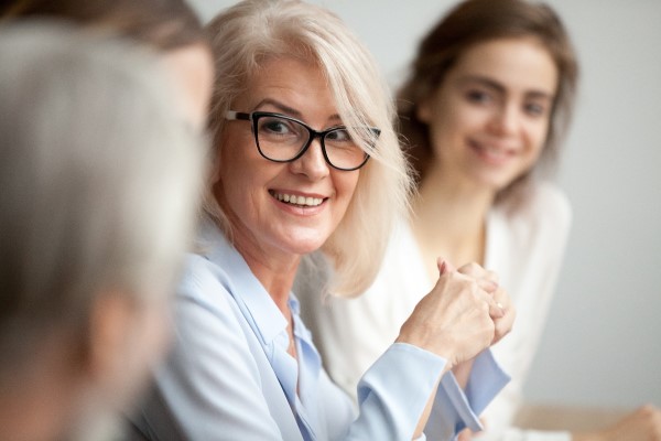 Smiling woman with glasses in a meeting.