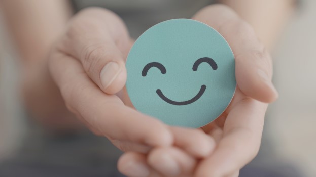 Hands holding a drawing of a smiley face