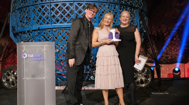 Comedian Ed Byrne (left) and CIRAS' Katie Healy (right) present Great Western Railway's Samantha Winfield (centre) with the Health and Wellbeing Award in the 2022 RailStaff Awards