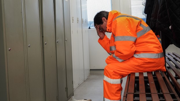 rail construction ports worker with mental health depression anxiety in locker room with head in his hands