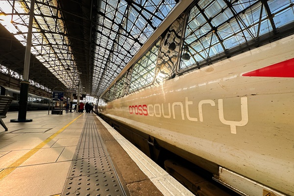 A CrossCountry train stopped at a station platform in Manchester, light streaming through the roof.