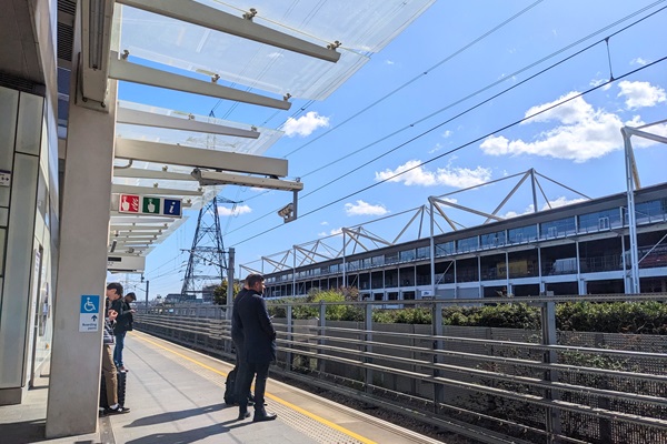 People wait on a sunny platform at Custom House station on the Elizabeth Line.