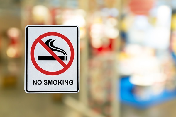 A "No Smoking" sign with a red circle and a crossed-out cigarette on a blurred background.