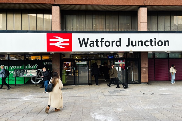 The exterior of Watford Junction station with its sign and people entering and exiting.