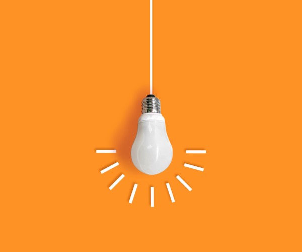 Lightbulb with paper rays around it on an orange background